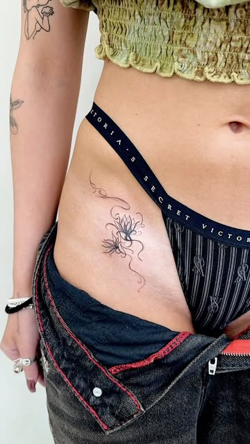 Black-and-grey fine-line ornamental tattoo at the hip